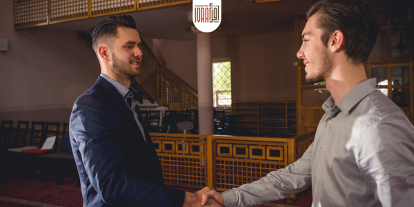 Two Muslim men shaking hands and exchanging Salam after prayer.